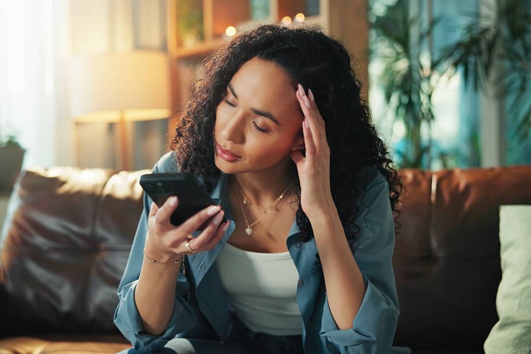 A woman reading a text and experiencing a headache.